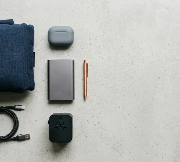 Accessoires de voyage disposés sur une surface épurée illustrant le choix entre essentiels et gadgets